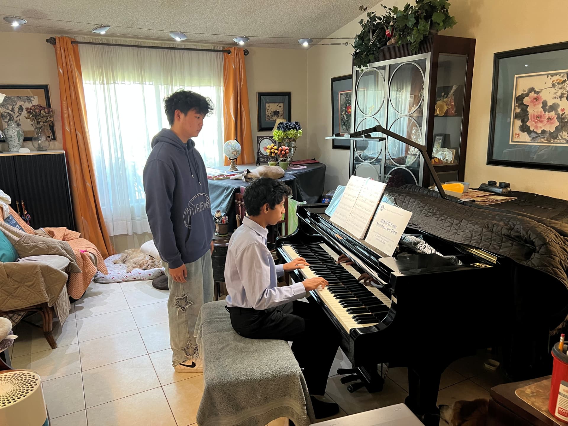 Brendan Li listening as a student performs at the piano